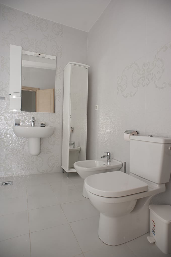 Bright bathroom with white fixtures, bidet, and mirror in a villa in Perazicha Do, Montenegro.