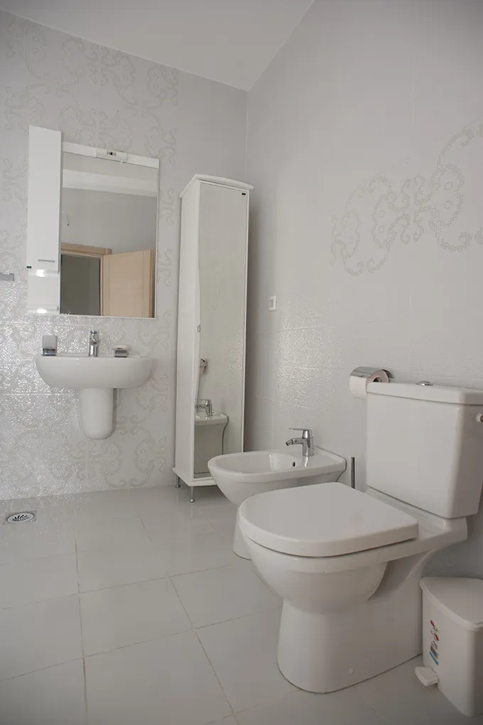 Helles Badezimmer mit weißer Sanitärkeramik, Bidet und Spiegel in einer Villa in Perazića Do, Montenegro.