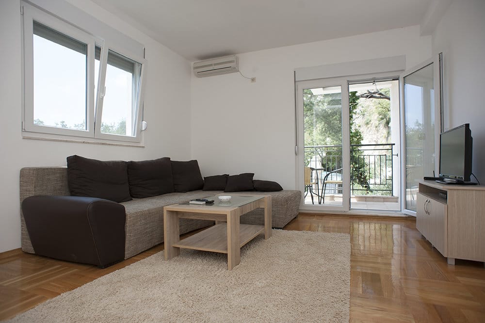 Bright living room with a sofa and access to the balcony in a villa, Perazića Do, Montenegro: modern interior and parquet flooring.