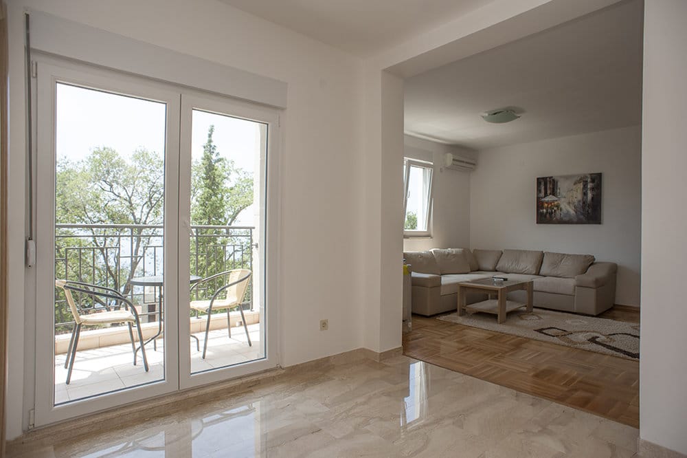 Living room with access to the terrace and sea view in a villa, Perazica Do, Montenegro: bright interior, parquet flooring and furniture.