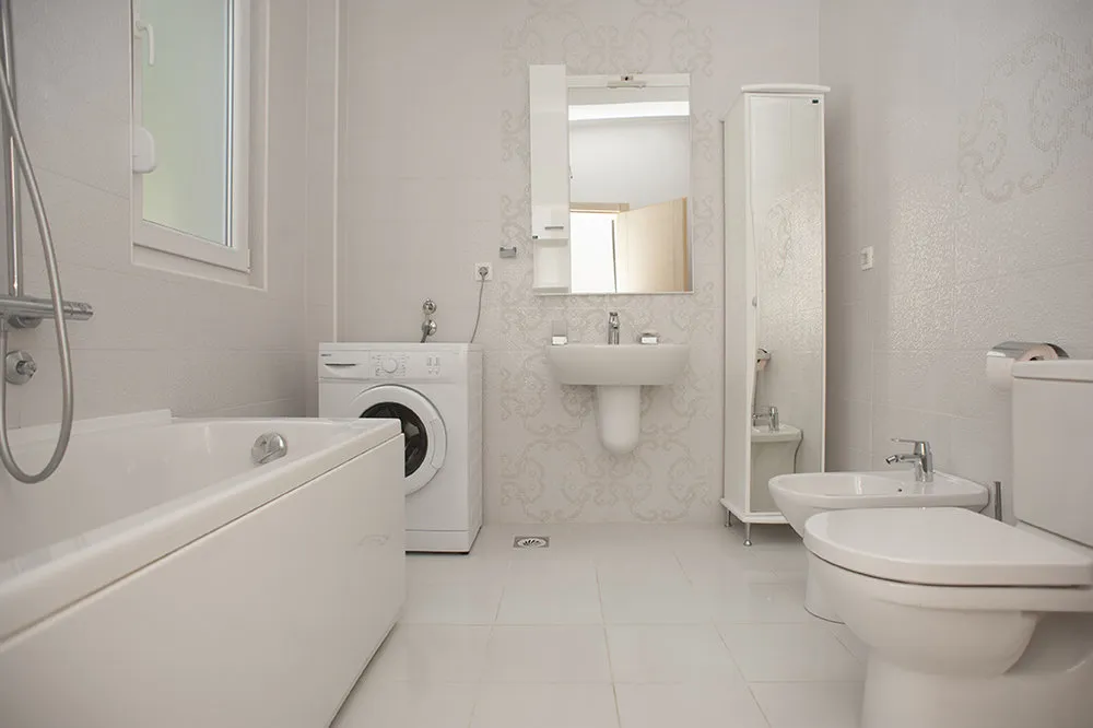 Helles Badezimmer mit Badewanne, Waschmaschine und Bidet in einer Villa in Perazića Do, Montenegro.