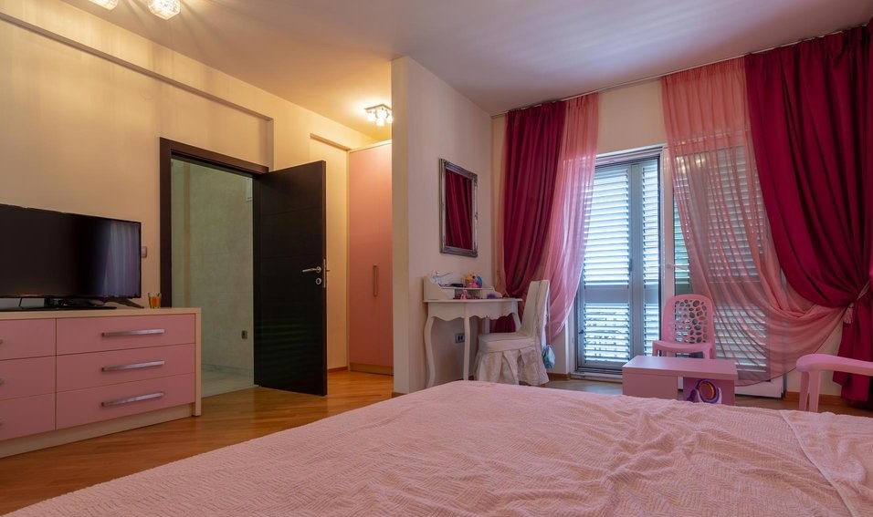 Schlafzimmer in Rosatönen in einer Villa in Tivat, Montenegro: Doppelbett, Schminktisch und Zugang zum Balkon.