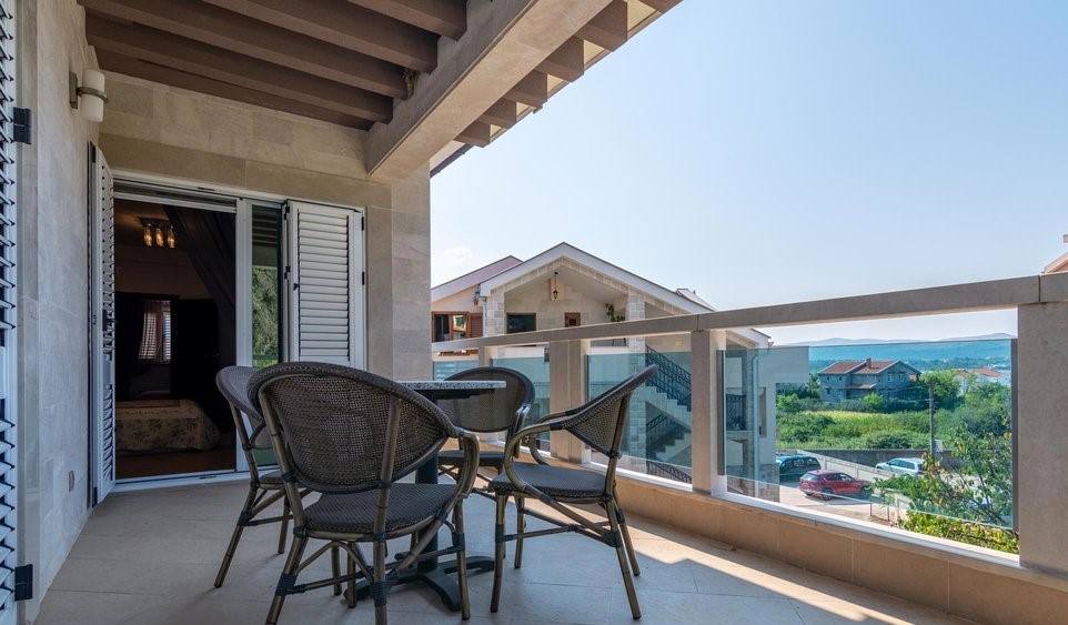 Terrasse der Villa in Tivat, Montenegro: geflochtene Möbel, Steinverkleidung und Panoramablick auf die Umgebung und das Meer.