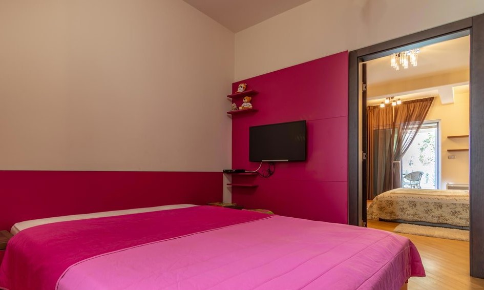 Schlafzimmer mit heller rosa Dekoration und Doppelbett in einer Villa in Tivat, Montenegro, Blick in den angrenzenden Raum.