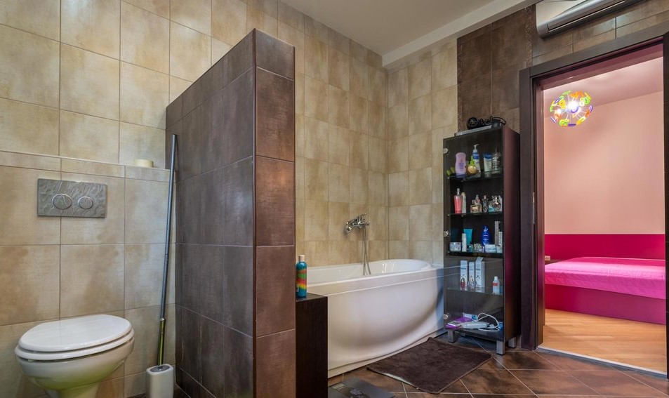 Modernes Badezimmer mit weißer Badewanne und Fliesenverkleidung in einer Villa in Tivat, Montenegro, Blick auf das Schlafzimmer.