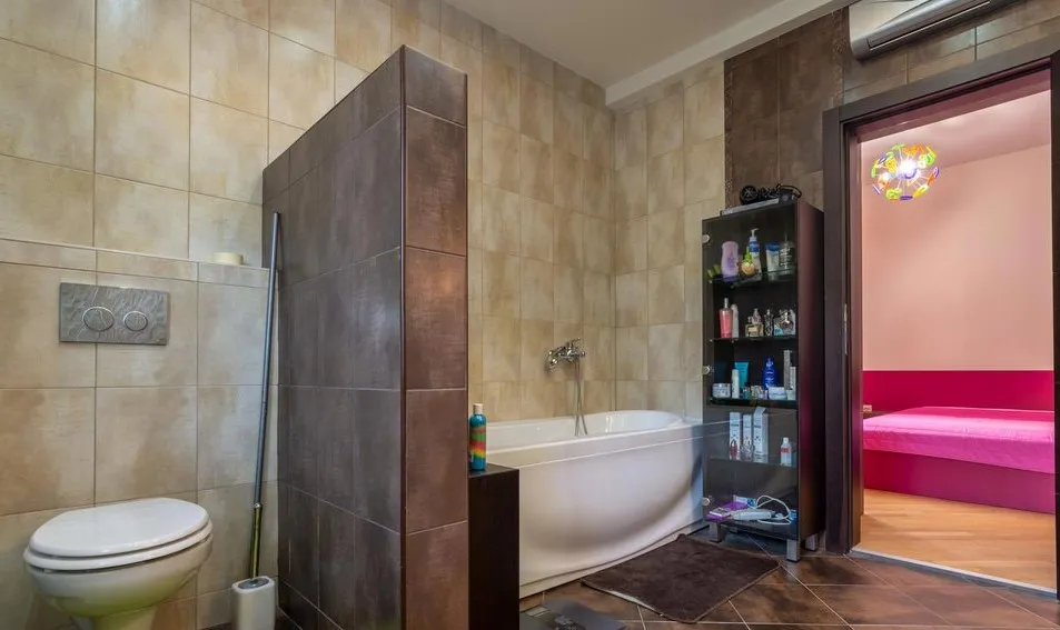 Modernes Badezimmer mit weißer Badewanne und Fliesenverkleidung in einer Villa in Tivat, Montenegro, Blick auf das Schlafzimmer.