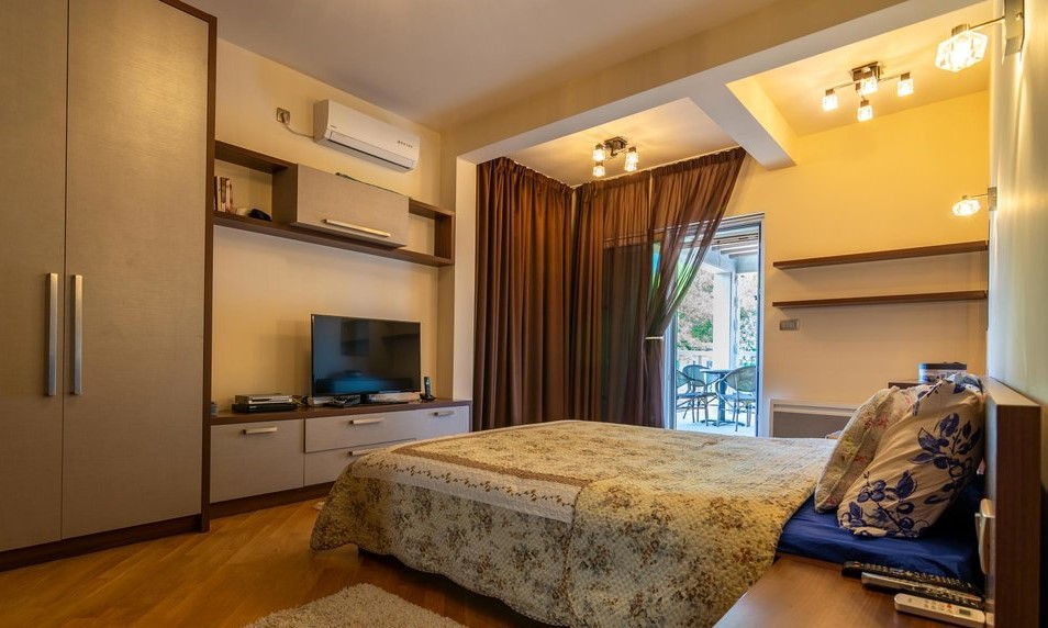 Gemütliches Schlafzimmer mit Doppelbett und Zugang zur Terrasse in einer Villa, Stadt Tivat, Montenegro. Moderne Möbel und TV.