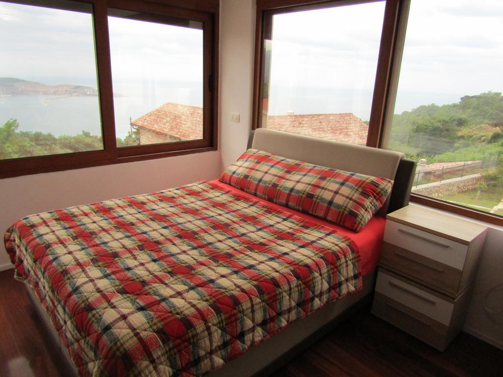 Schlafzimmer mit Panoramablick auf das Meer in einem Haus, Šušanj, Bar-Riviera, Montenegro: Doppelbett und Holzboden.