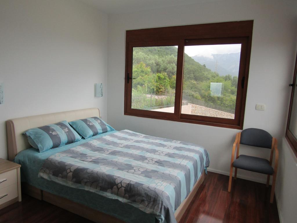 Schlafzimmer in einem Haus in Šušanj, Bar Riviera, Montenegro: Doppelbett, Holzboden und Bergblick aus dem Fenster.