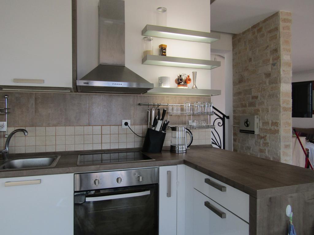 Moderne Küche in einem Haus in Šušanj, Bar Riviera, Montenegro: weiße Fronten, Steinverkleidung und Einbaugeräte.