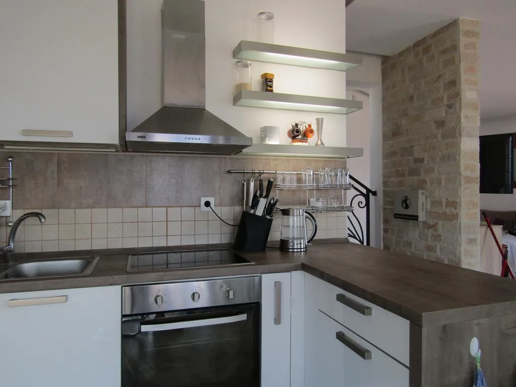 Moderne Küche in einem Haus in Šušanj, Bar Riviera, Montenegro: weiße Fronten, Steinverkleidung und Einbaugeräte.