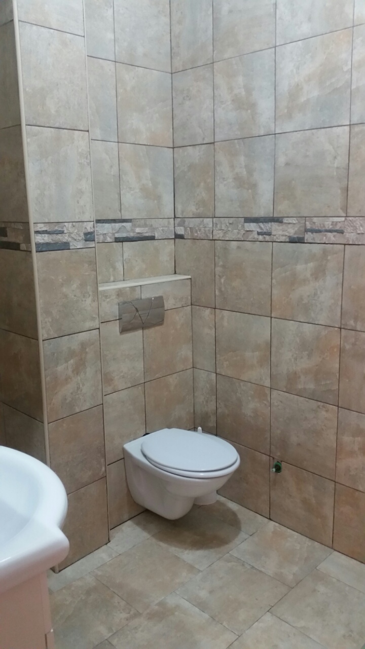 Savremeno kupatilo u stanu u Budvi, Crna Gora: viseća WC šolja i obloga od bež pločica u imitaciji kamena.