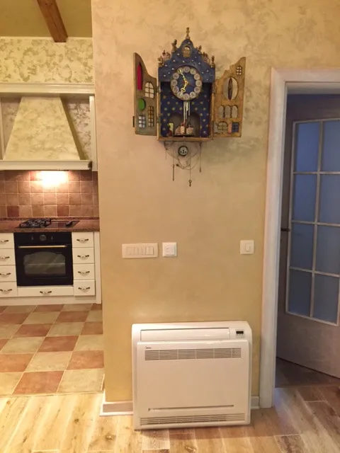 Wnętrze kuchni w domu w Zelenice, Czarnogóra: dekoracyjny zegar na ścianie, stojący klimatyzator i płytki w stylu prowansalskim.
