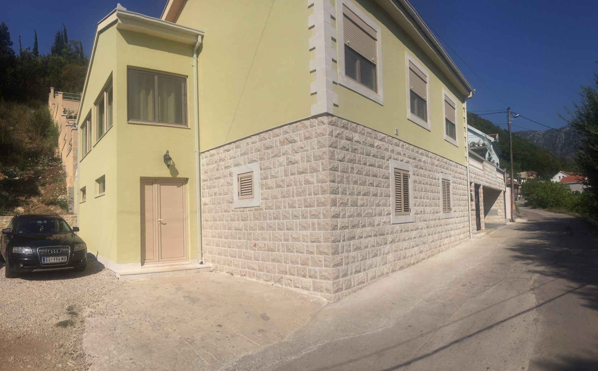 Two-story house in Zelenika, Montenegro: stone and stucco facade, parking and mountain view, building exterior.