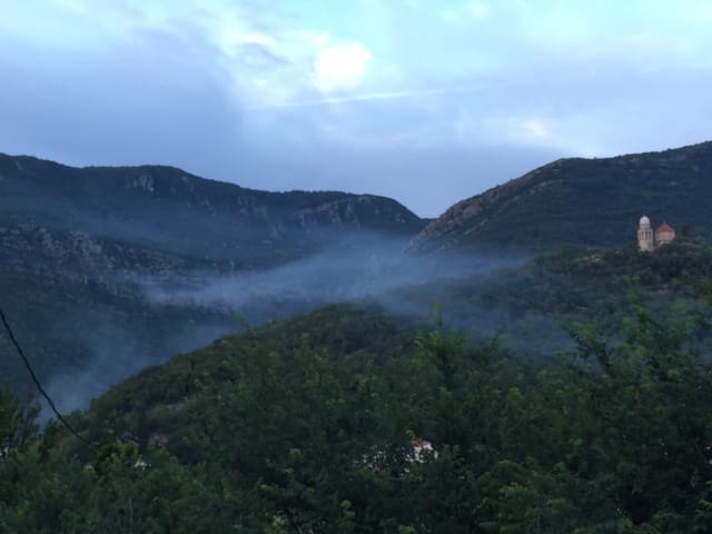 Panoramic view of the mountains and an old church in Zelenika, Montenegro: a picturesque landscape with mist over the forest.