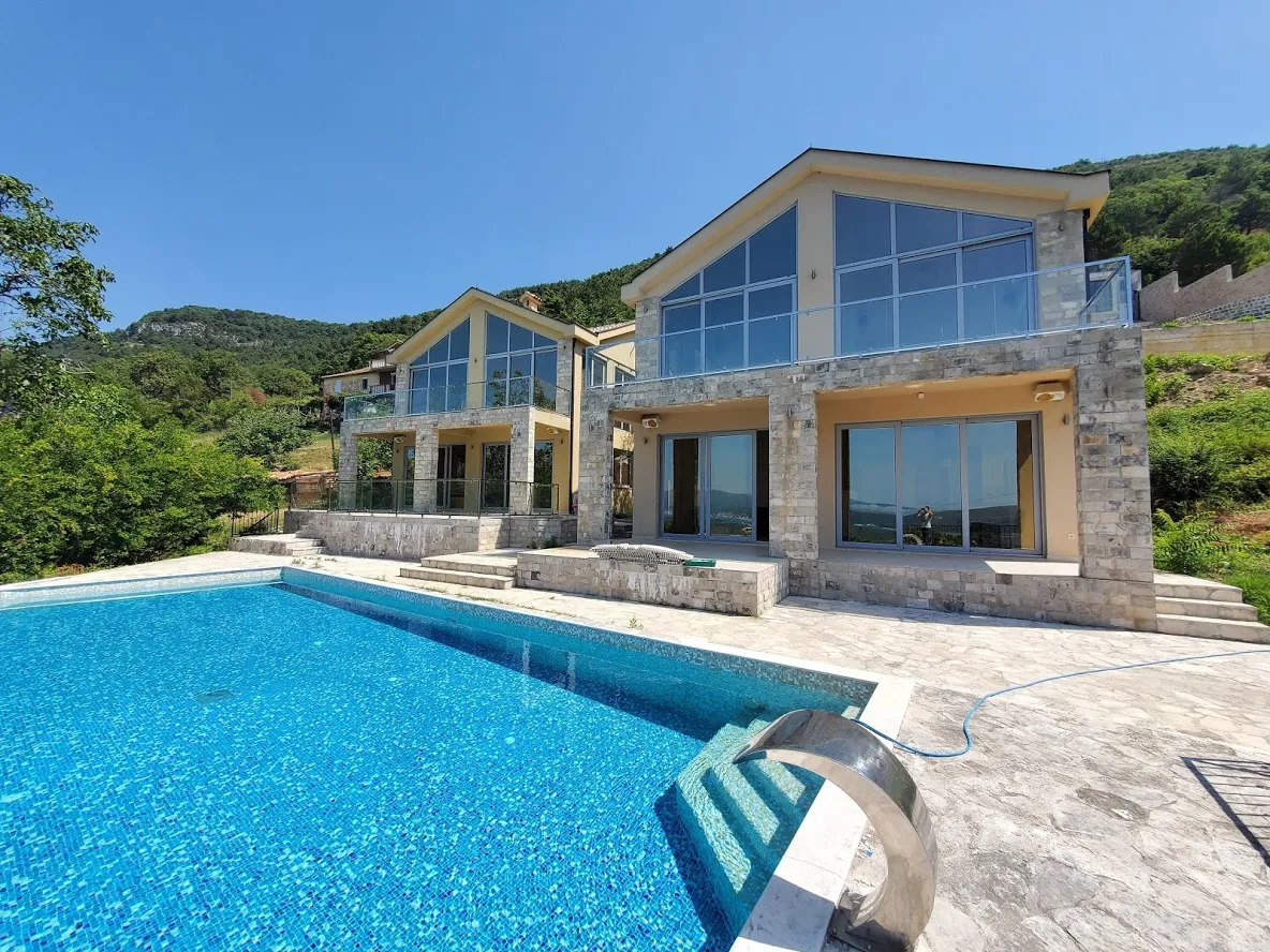 Large swimming pool in front of modern stone villas in the mountains