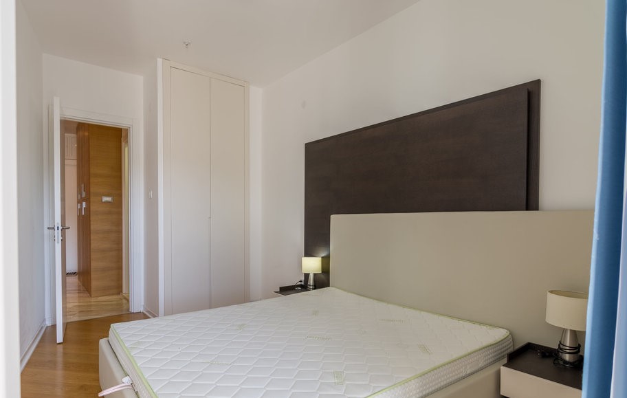 Budva, Karadağ’daki bir dairede çift kişilik yatak ve gömme dolaplı modern yatak odası.