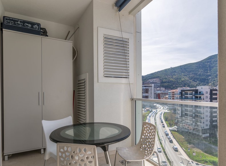 Budva, Karadağ’daki dairede balkon: cam masalı yemek alanı ve dağlar ile şehre manzara.