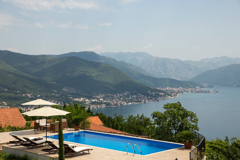 Offener Pool in einer Villa in Luštica, Montenegro, mit Panoramablick auf die Bucht von Kotor und die Berge, Sonnenliegen und Terrasse.