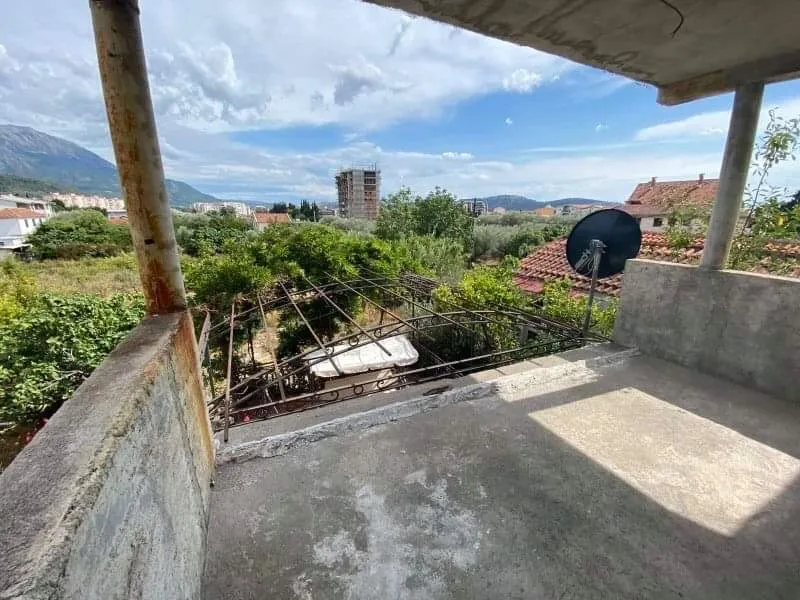 Otvorena terasa kuće u Šušnju, Crna Gora, sa pogledom na planine, zeleni vrt i gradsku izgradnju, u fazi završnih radova.