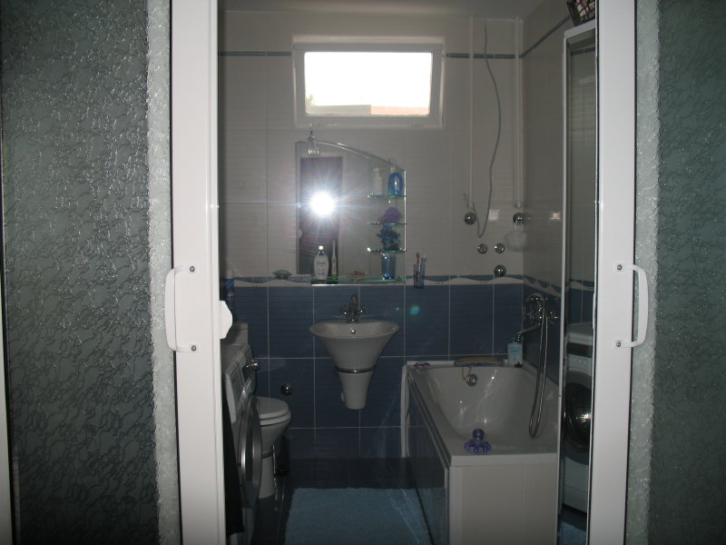 Kupatilo u kući u Šušnju, Crna Gora: plave pločice, kada, lavabo, ogledalo i veš mašina.