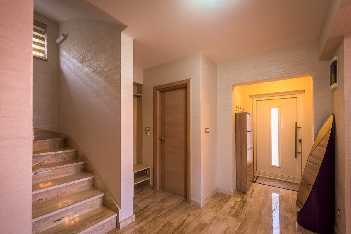 Eingangsbereich einer Villa in Krašići, Montenegro: Marmortreppe, helle Wandgestaltung, Eingangstür und moderne Möbel.