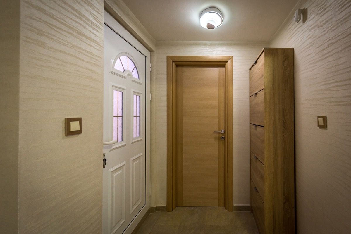 Heller Eingangsbereich einer Villa in Krašići, Montenegro: weiße Eingangstür, Zimmertür und ein Kleiderschrank in Holzoptik.