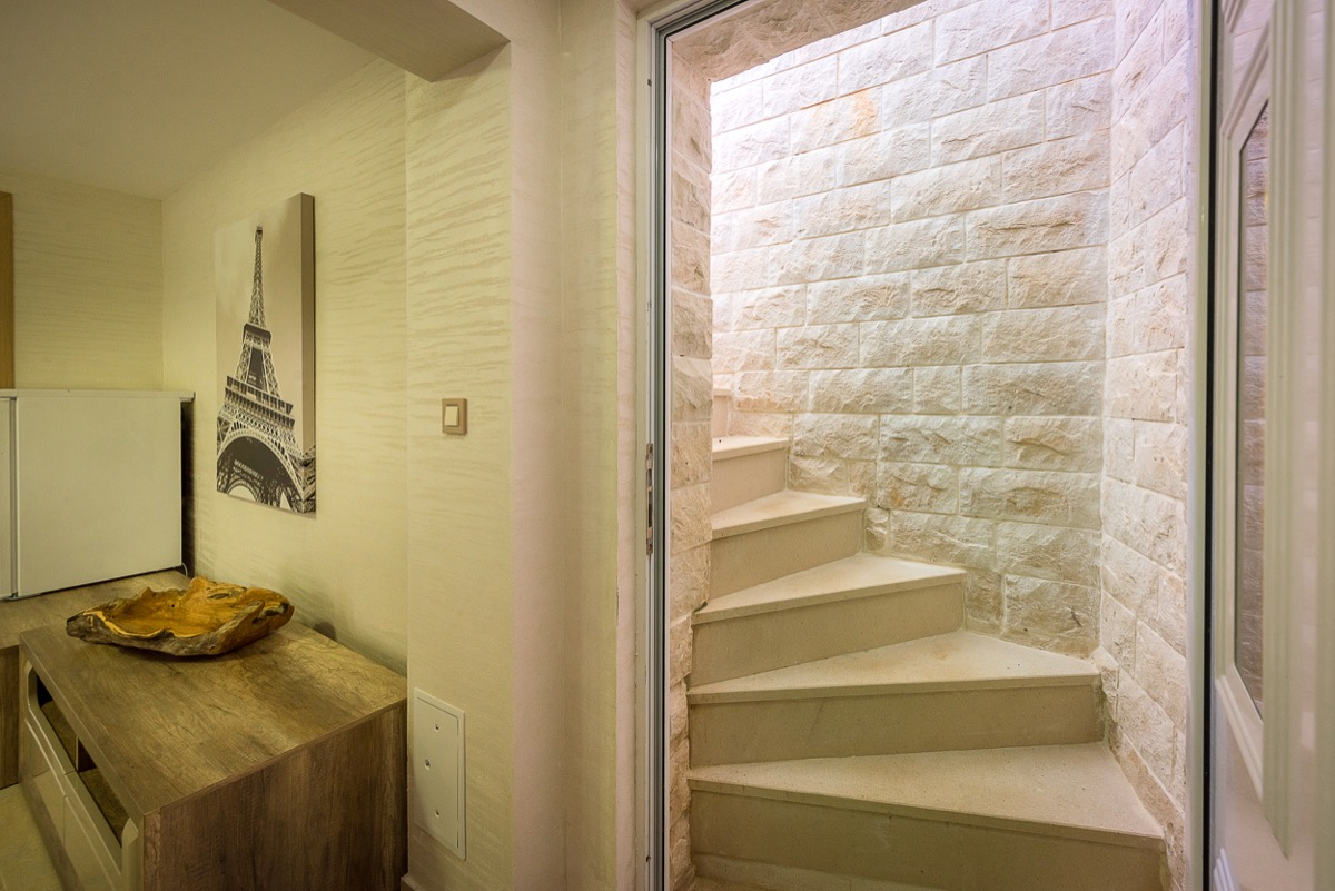 Wohnzimmer einer Villa in Krašići, Montenegro: steinerne Wendeltreppe, Holzmöbel und Dekor in einem modernen Interieur.