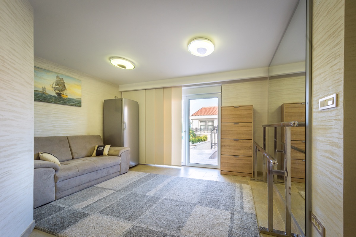 Wohnzimmer mit Sofa und Zugang zur Terrasse in einer Villa in Krašići, Montenegro: modernes Interieur und helle Ausstattung.