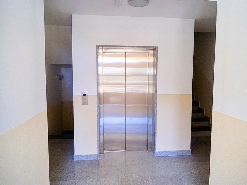 Un couloir avec une porte d'ascenseur dans un immeuble résidentiel