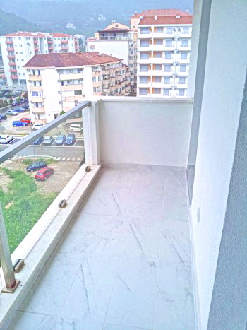 Budva, Karadağ’daki bir konut kompleksinde, şehir manzaralı, fayans zeminli ve cam korkuluklu aydınlık balkon.