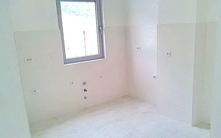 Ansicht einer Küche mit einem Fenster und weiß gefliesten Wänden