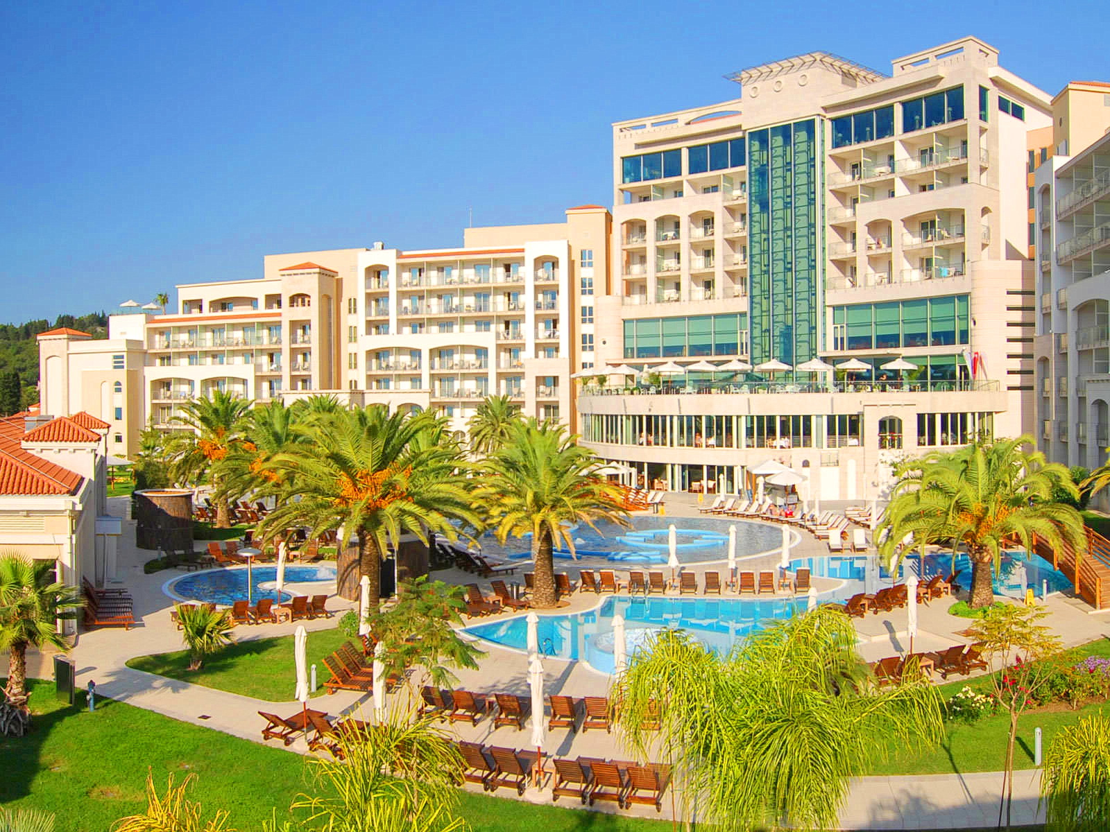Becici, Karadağ'da havuzlar, palmiyeler ve dinlenme alanı bulunan modern konut kompleksi. Tatil bölgesinin görünümü.