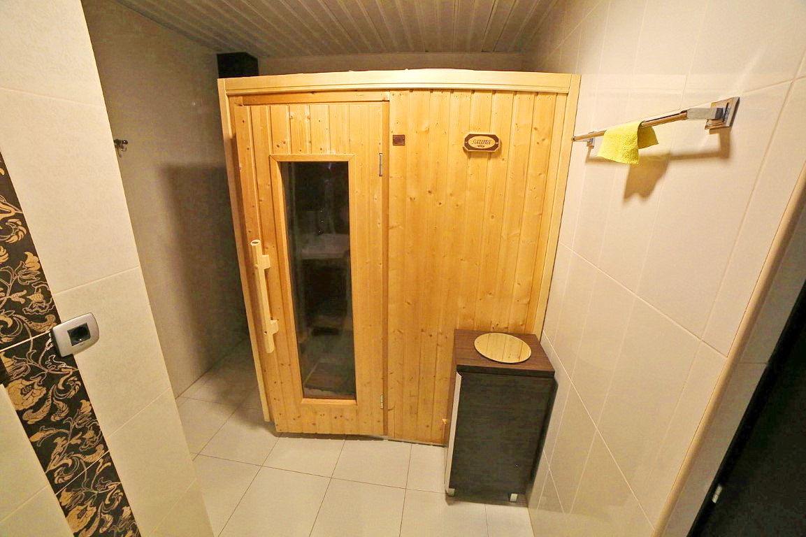 Badezimmer mit Holzsauna in einer Villa in Budva, Montenegro: moderne Fliesenverkleidung und stilvolle Möbel.