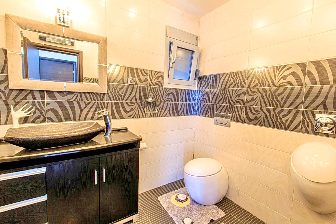 Badezimmer in einer Villa in Budva, Montenegro: stilvolle Sanitäranlagen, Waschtischunterschrank und Fliesen mit Zebra-Print.