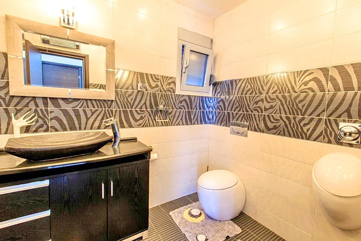 Badezimmer in einer Villa in Budva, Montenegro: stilvolle Sanitäranlagen, Waschtischunterschrank und Fliesen mit Zebra-Print.