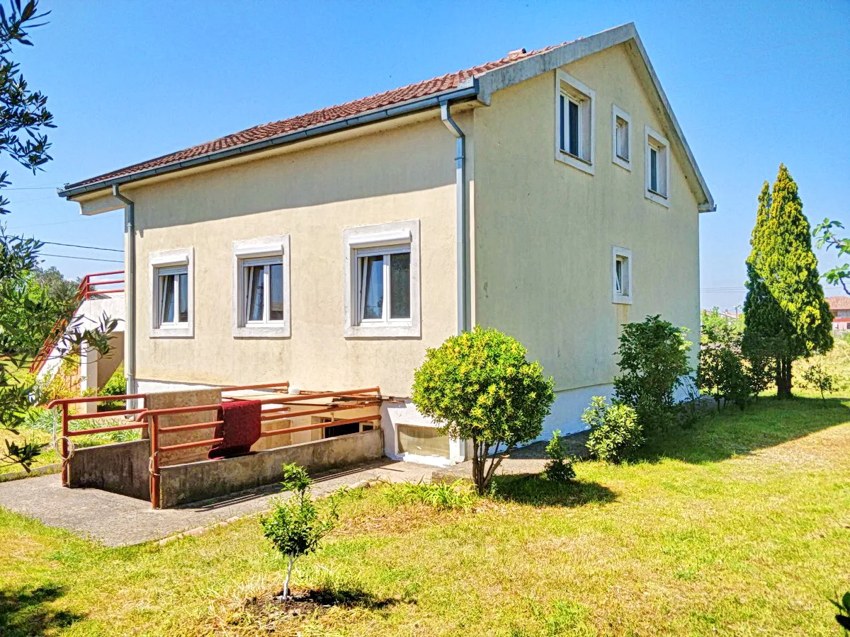 Pogled na eksterijer dvospratne kuće sa dvorištem i malim grmom.