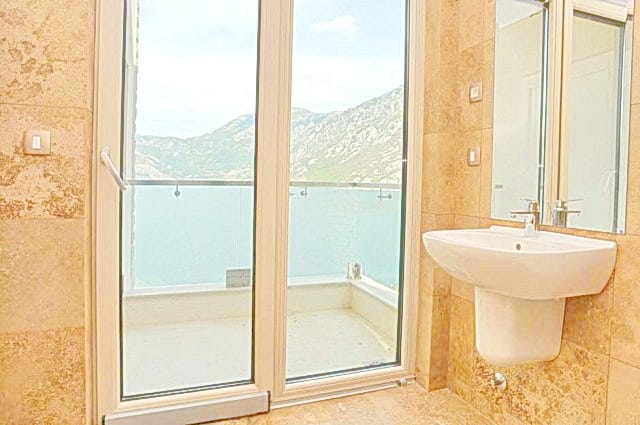 Deniz ve dağ manzaralı banyo, konut kompleksinde, Morinj, Karadağ: bej fayanslar ve panoramik balkon.