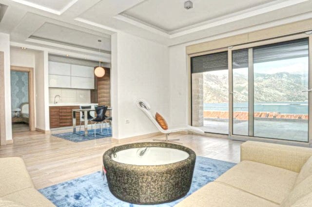 Karadağ, Morinj’deki konut kompleksinde deniz manzaralı modern oturma odası: aydınlık iç mekân, panoramik pencereler ve mutfak.