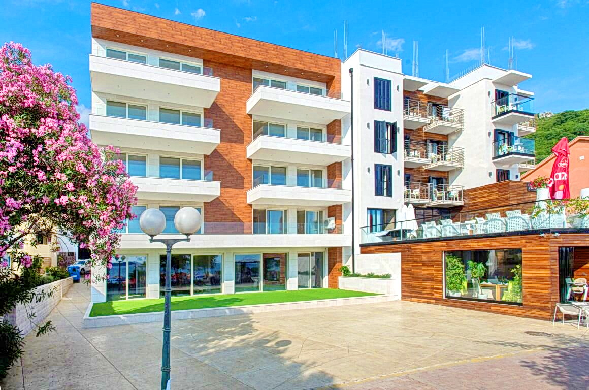Rafailoviçi, Karadağ’da balkonları ve ahşap kaplaması olan modern konut kompleksi, teraslı bina cephesinin görünümü.