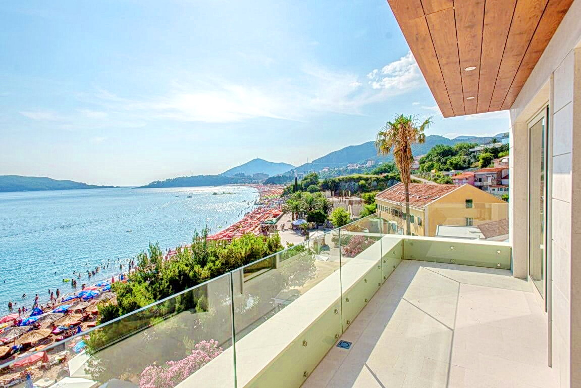 Karadağ, Rafailovići’de deniz ve plaj manzaralı geniş balkon, modern kaplama ve cam korkuluklar.