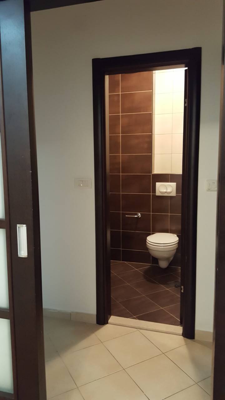 Budva, Karadağ’daki dairede kahverengi fayanslı ve duvara asılı klozetli modern banyo.