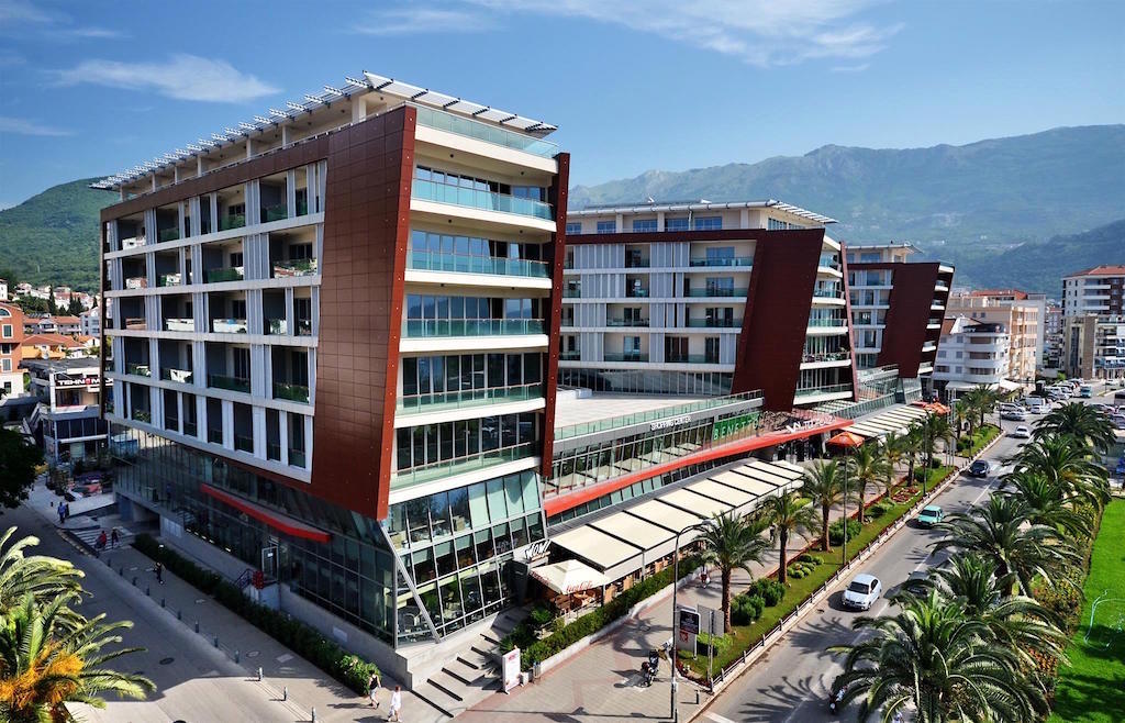 Moderner Wohnkomplex mit Einkaufszentrum in Budva, Montenegro: Blick auf die Fassade des Gebäudes mit Panoramabalkonen.