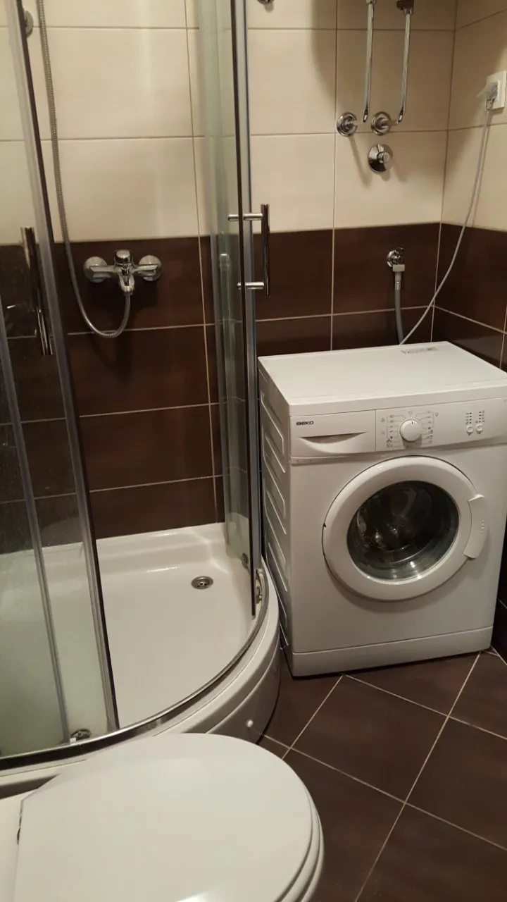Badezimmer mit Duschkabine, Waschmaschine und Toilette.