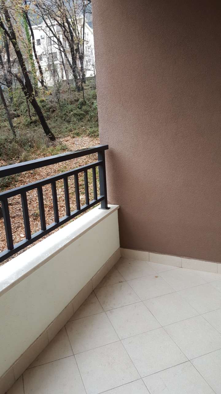 Budva, Karadağ’daki bir dairede, orman parkı alanına bakan, fayans zeminli ve metal korkuluklu balkon.