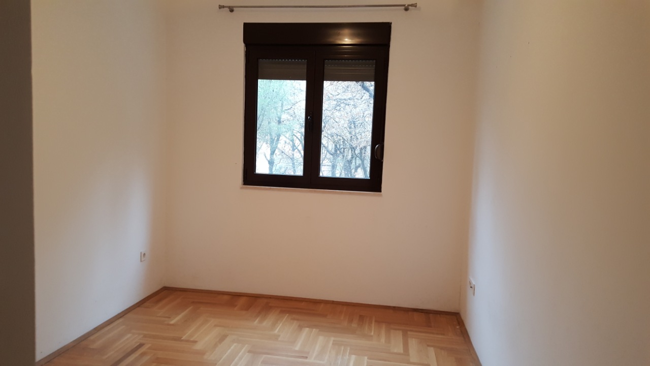 Parkeli ve pencereli aydınlık boş yatak odası, dairede, Budva, Karadağ. Ağaç manzarası, kaliteli işçilik.