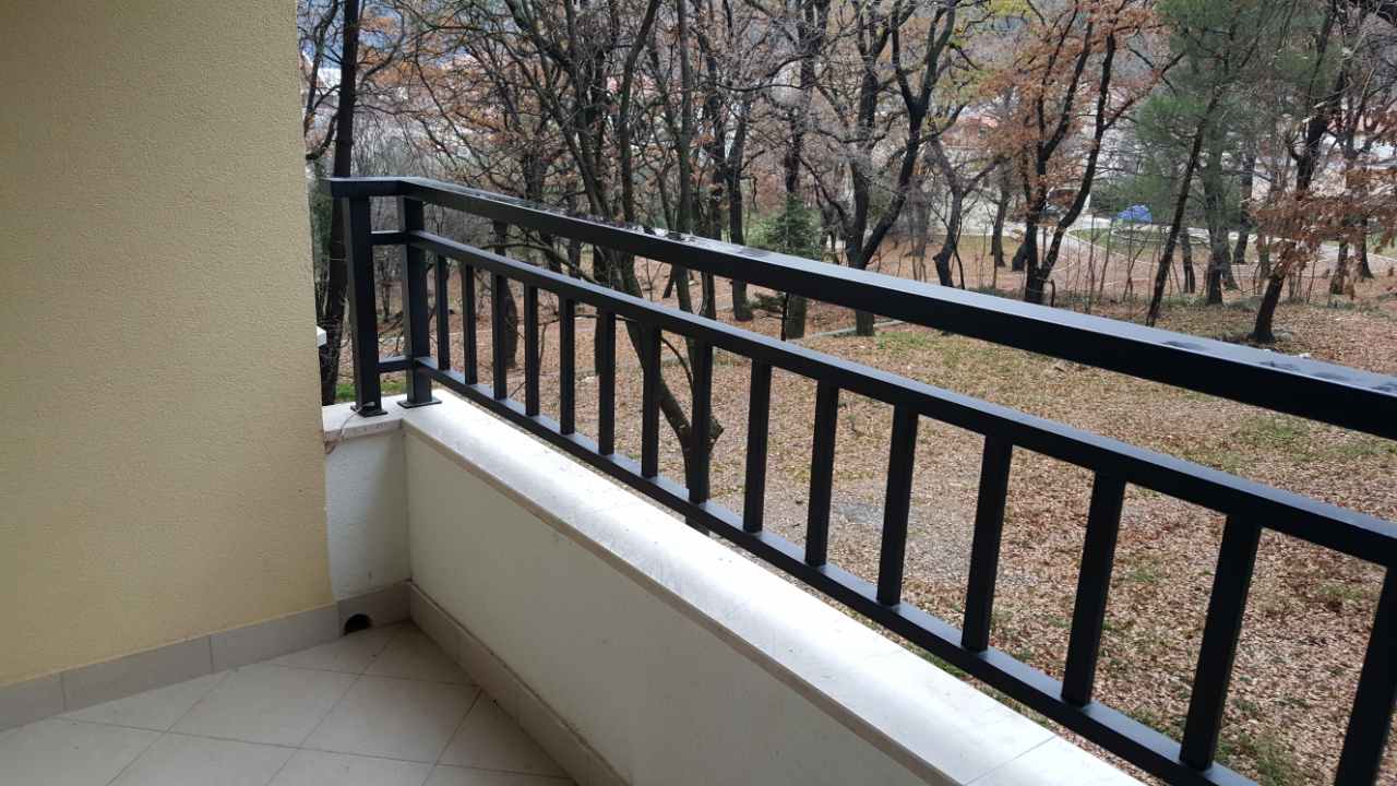 Budva, Karadağ’daki dairede siyah metal korkuluklu ve orman parkı manzaralı balkon.