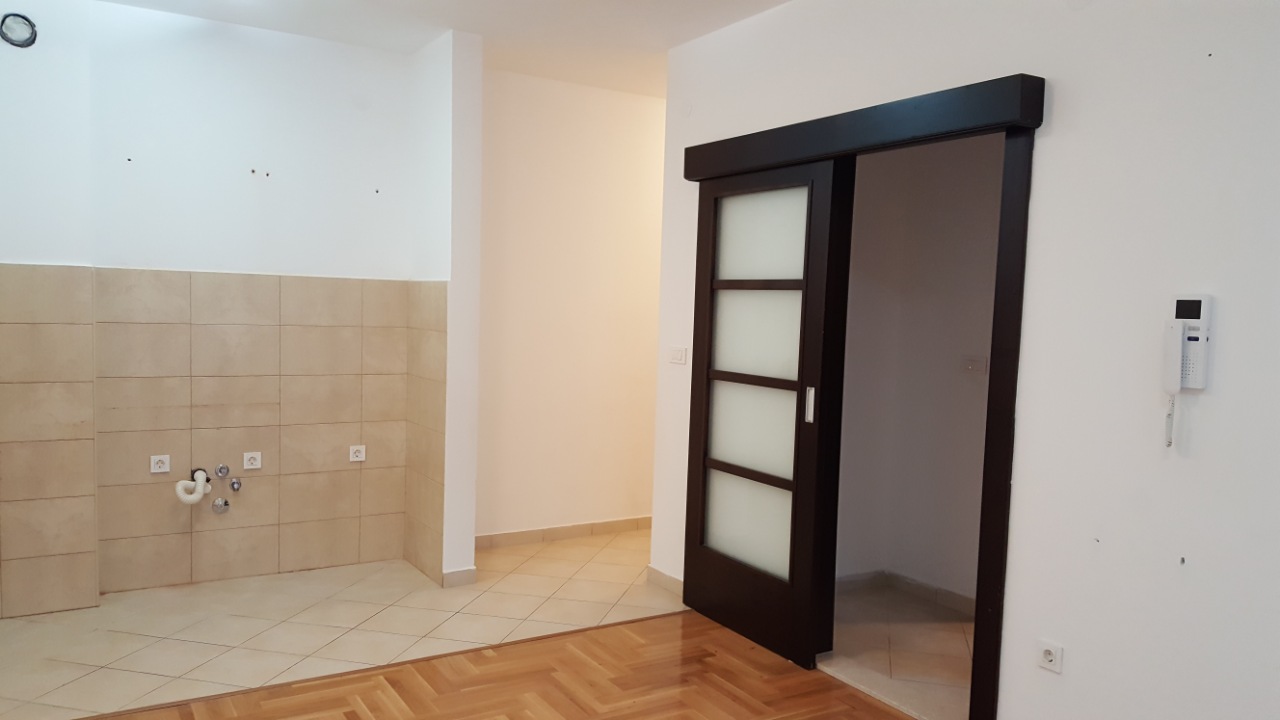 Budva, Karadağ’daki bir dairede mutfak iç mekanı: açık renkli kaplama, fayans backsplash, parke ve sürgülü iç kapı.