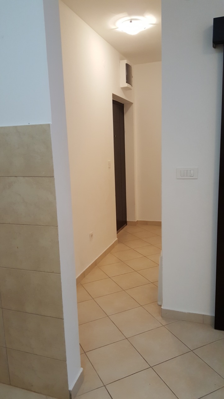 Beyaz duvarlı ve fayans zeminli aydınlık koridor, dairede, Budva, Karadağ. Kapı ve aydınlatmalı giriş alanı.