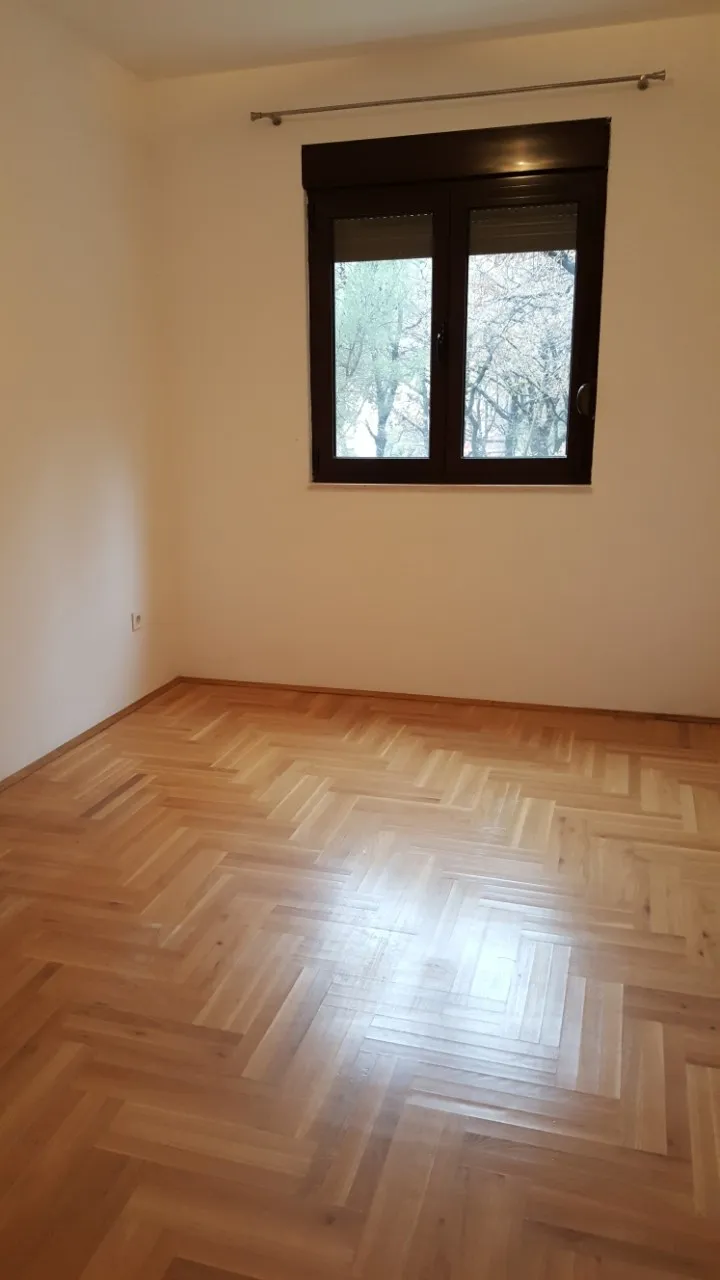 Leerer Raum mit Parkettboden und dunklem Fenster an der Wand
